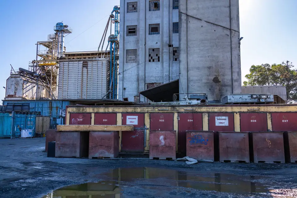 Rangée de grandes bennes à déchets au pied d'un silo à grains