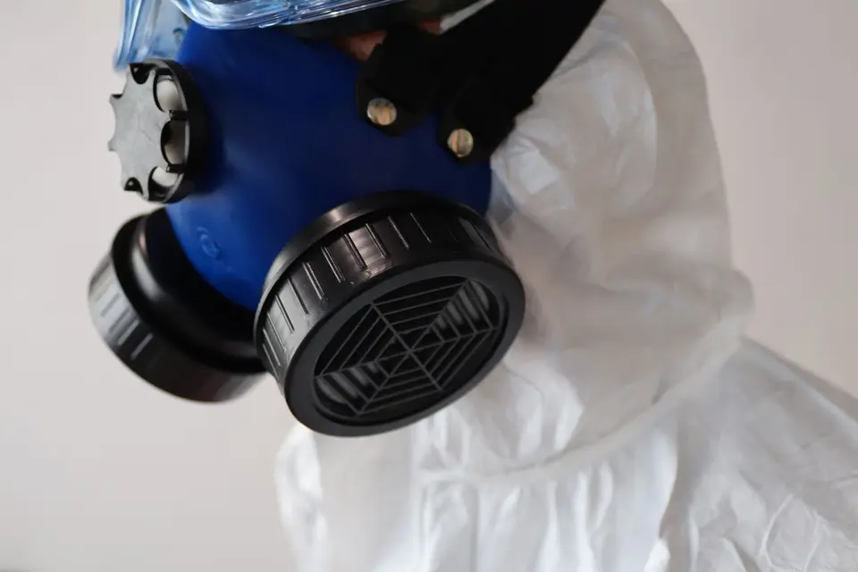 Masque respiratoire à cartouches porté avec une combinaison blanche de protection